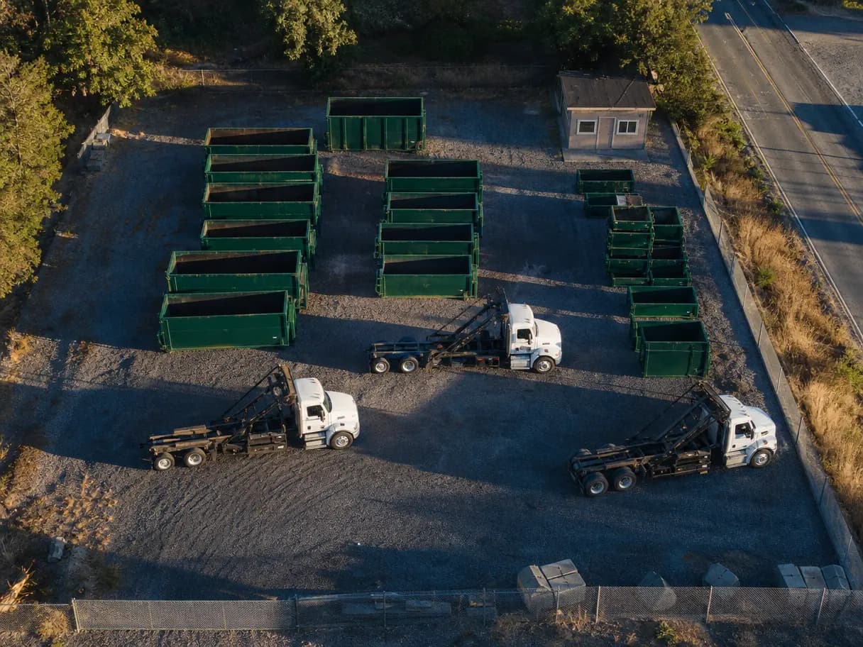 Aerial view of a dumpster yard with cans lined up by size and three trucks.